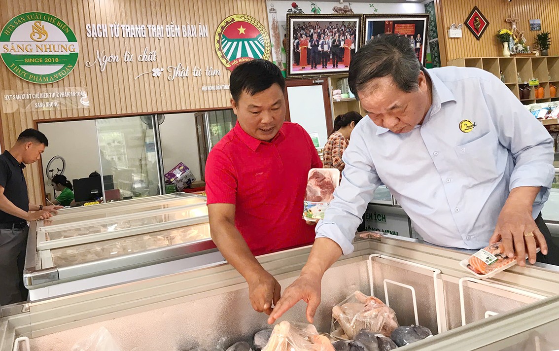 Anh Nguyễn Ngọc Sáng (áo đỏ) giới thiệu các sản phẩm nổi bật tại chuỗi cửa hàng “Nông sản xanh Sáng Nhung” cho TSKH. Hà Phúc Mịch, Chủ tịch Hiệp hội Nông nghiệp Hữu cơ Việt Nam.